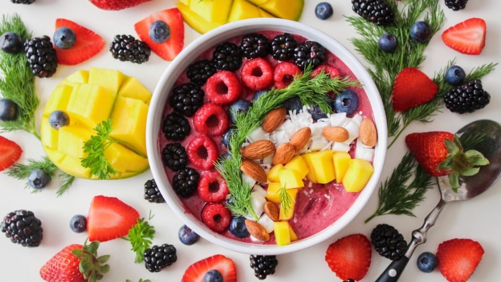 A picture of a bowl of custard with a lot of freshly cut fruits and dry fruits on top, being photographed